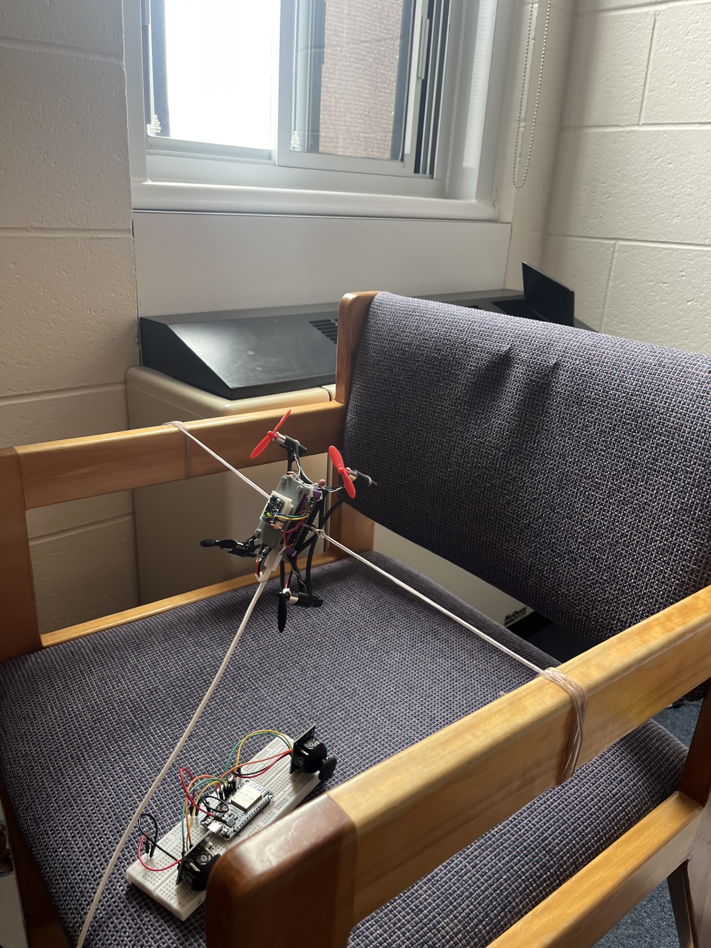 Quadcopter restrained in a multi-direction tether rig beside its controller